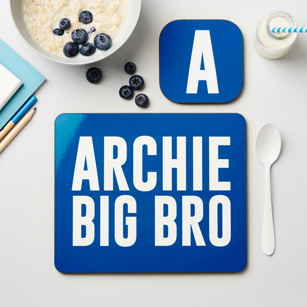 Blue placemat with 'ARCHIE BIG BRO' text on a table with breakfast items