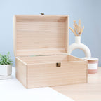 Wooden jewelry box on a light blue background with decorative items.