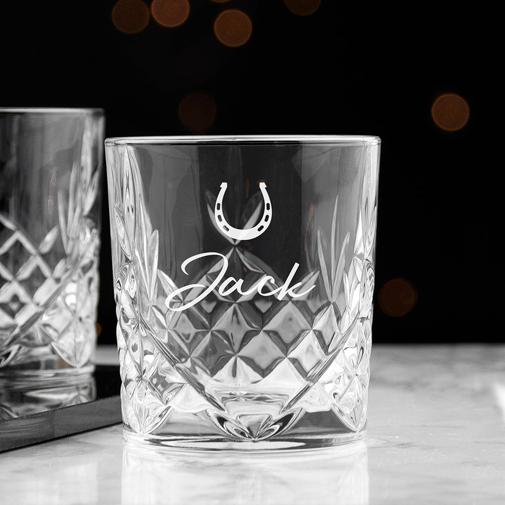 Crystal glass with engraved name and horseshoe symbol on a dark background