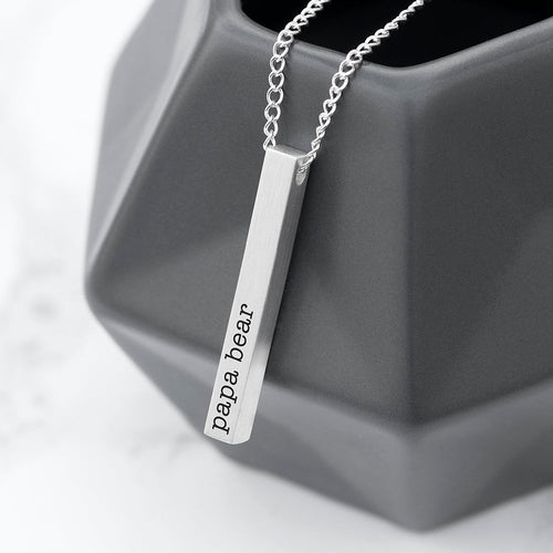 Silver necklace with 'papa bear' pendant on a gray geometric object