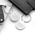Two silver keychains with engraved text on a white surface.
