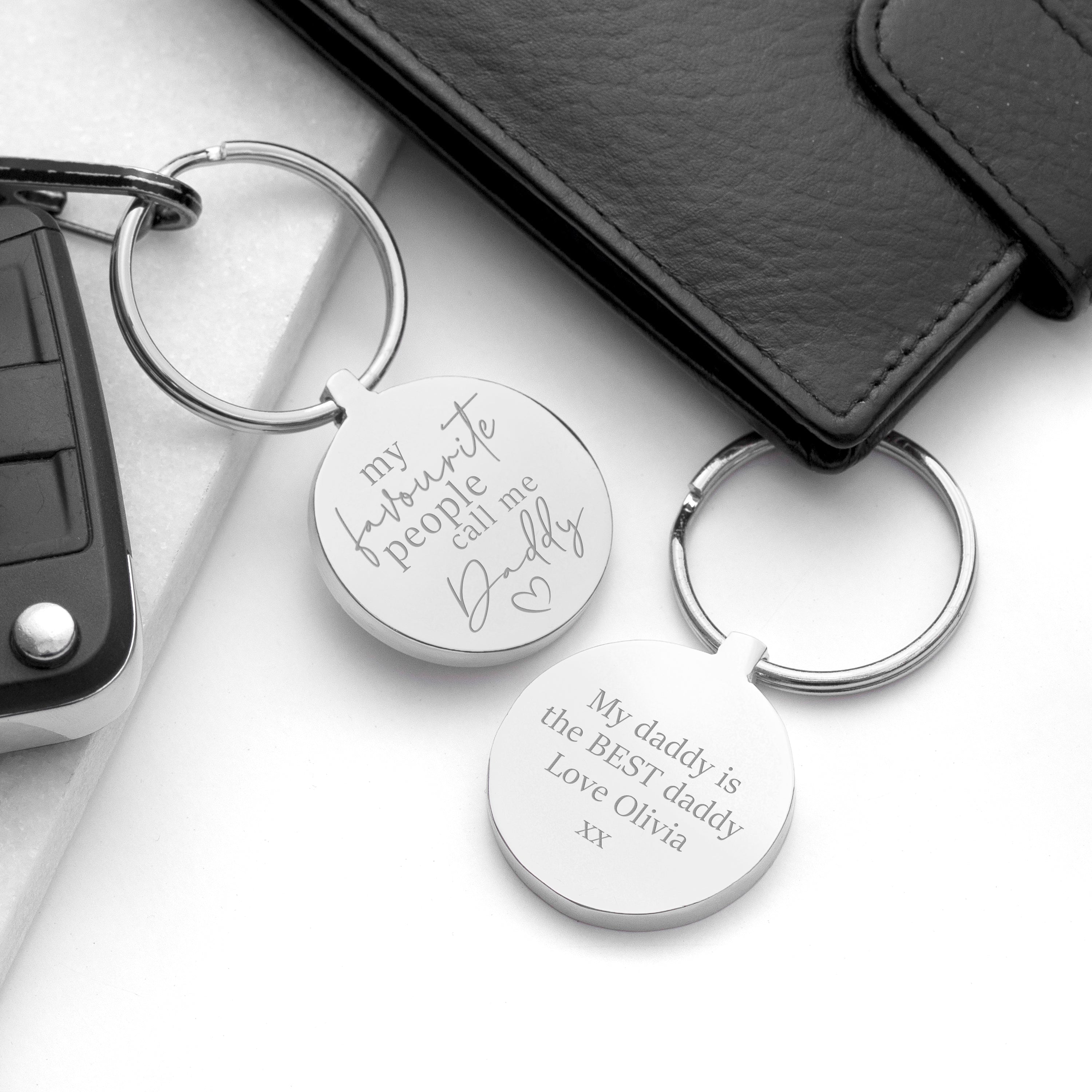 Two silver keychains with engraved text on a white surface.