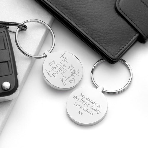 Two silver keychains with engraved text on a white surface.