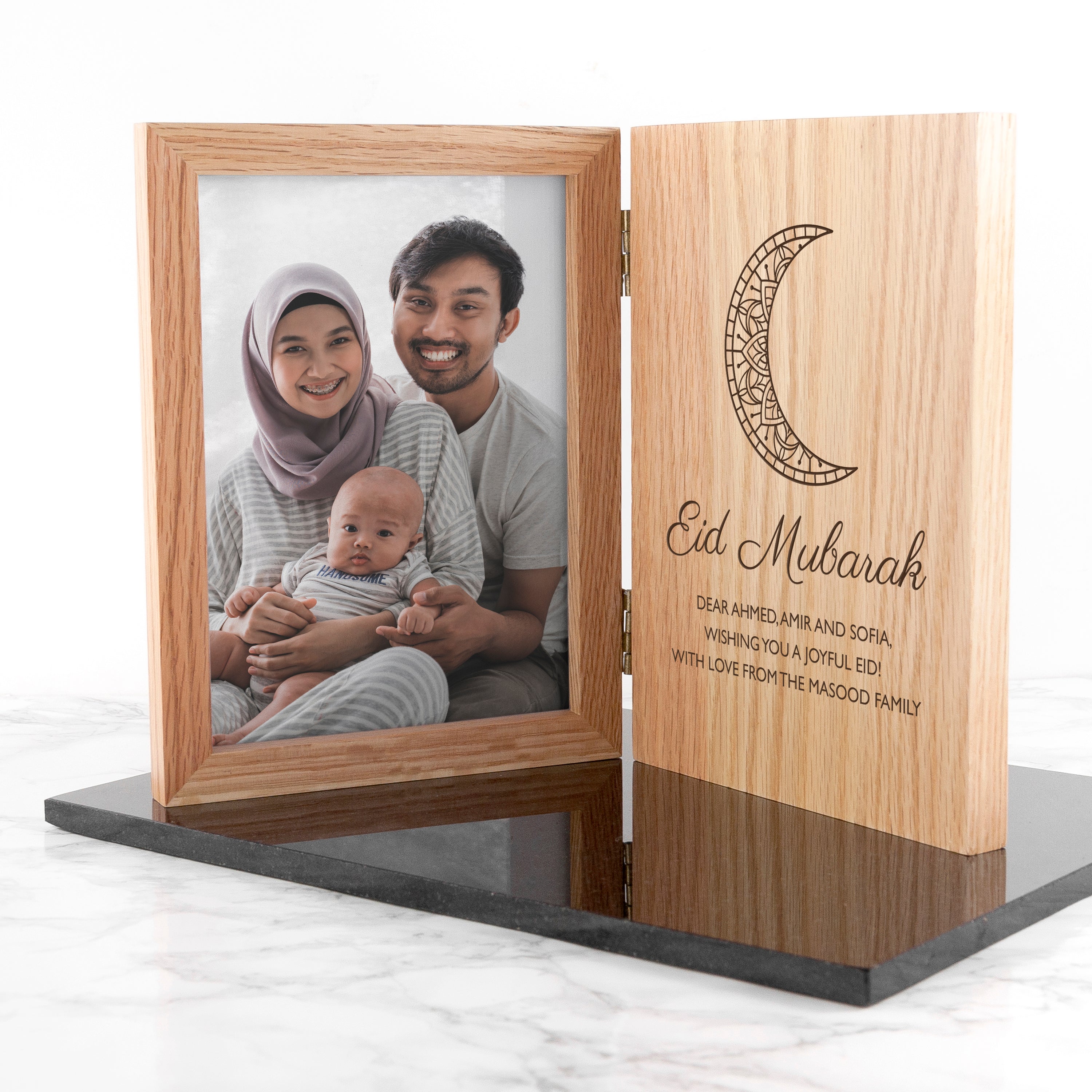 Wooden photo frame with a family portrait and 'Eid Mubarak' message on a white background
