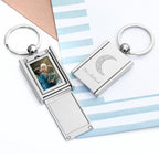 Silver keychain with photo display and engraved design on a striped background