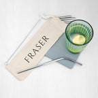 Metal straws with a branded pouch and a green glass on a white background