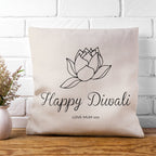 Decorative pillow with 'Happy Diwali' text and lotus design on a white brick wall background.