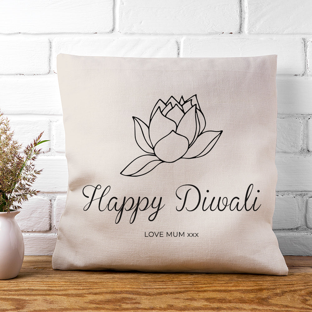 Decorative pillow with 'Happy Diwali' text and lotus design on a white brick wall background.