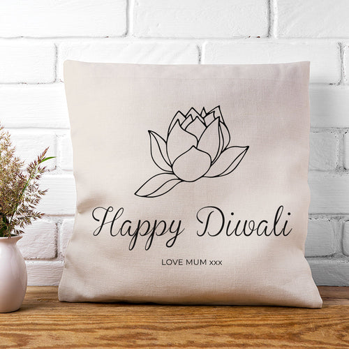 Decorative pillow with 'Happy Diwali' text and lotus design on a white brick wall background.