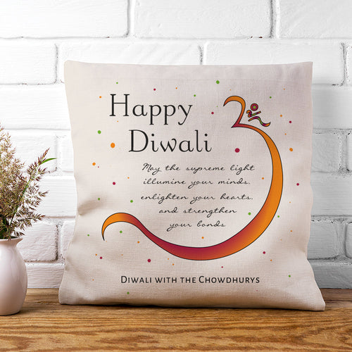 Decorative pillow with 'Happy Diwali' message on a wooden surface with a white brick wall background.