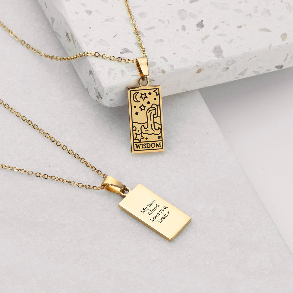 Gold necklace with two pendants on a light gray surface