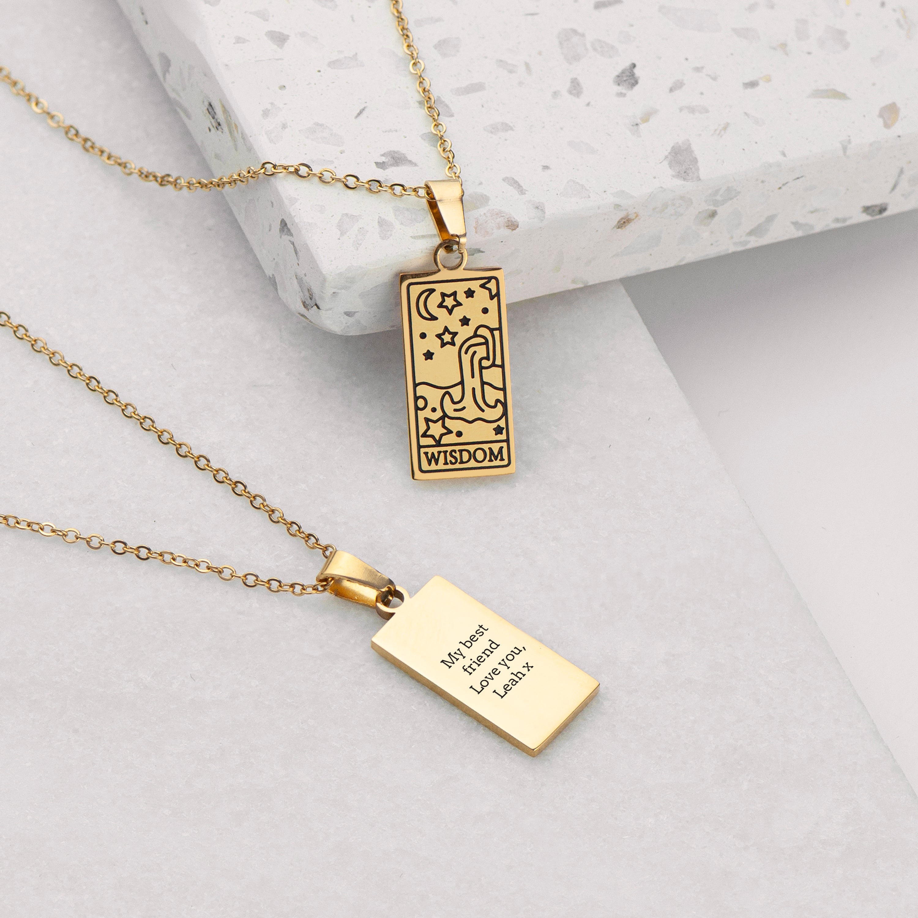 Gold necklace with two pendants on a light gray surface