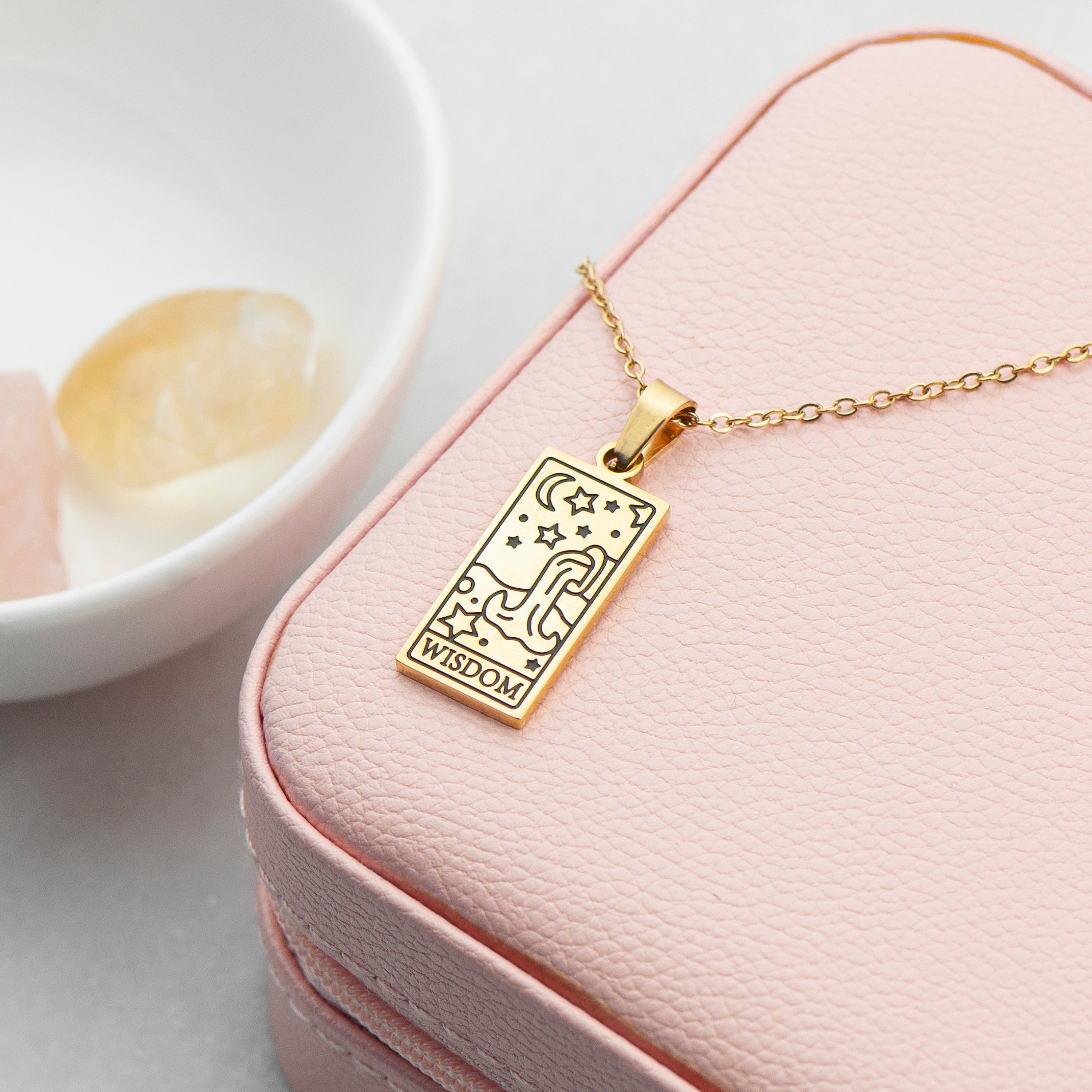 Gold necklace with a pendant on a pink jewelry box