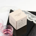 Wooden box labeled 'Cosy Movie Night' on a black surface with lace, next to pink drinks.