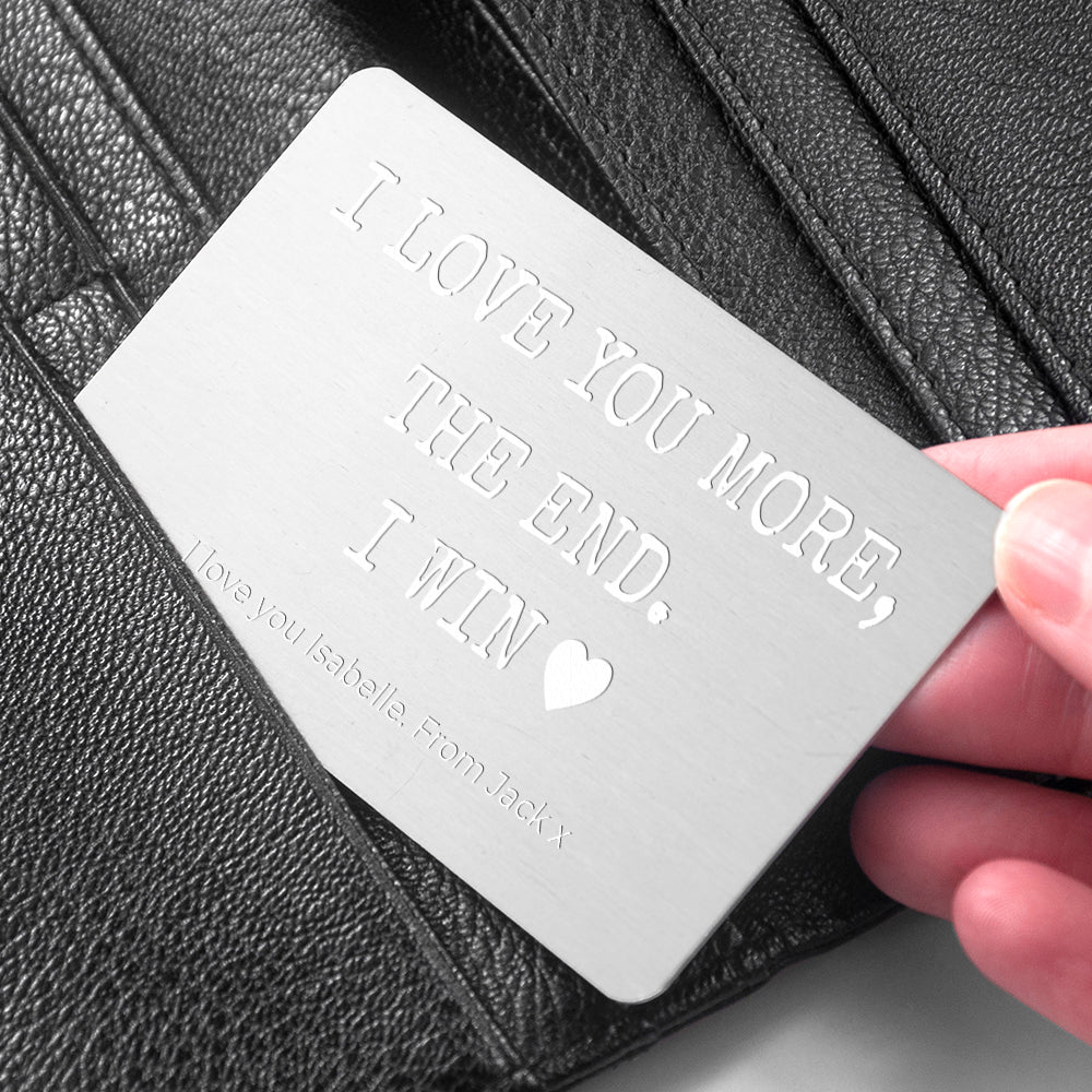 Personalized metal card with engraved text held over a black leather surface
