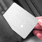 Personalized metal card with engraved text held over a black leather surface