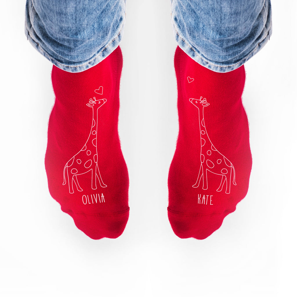 Red socks with giraffe illustrations and names 'Olivia' and 'Kate' on a white background.