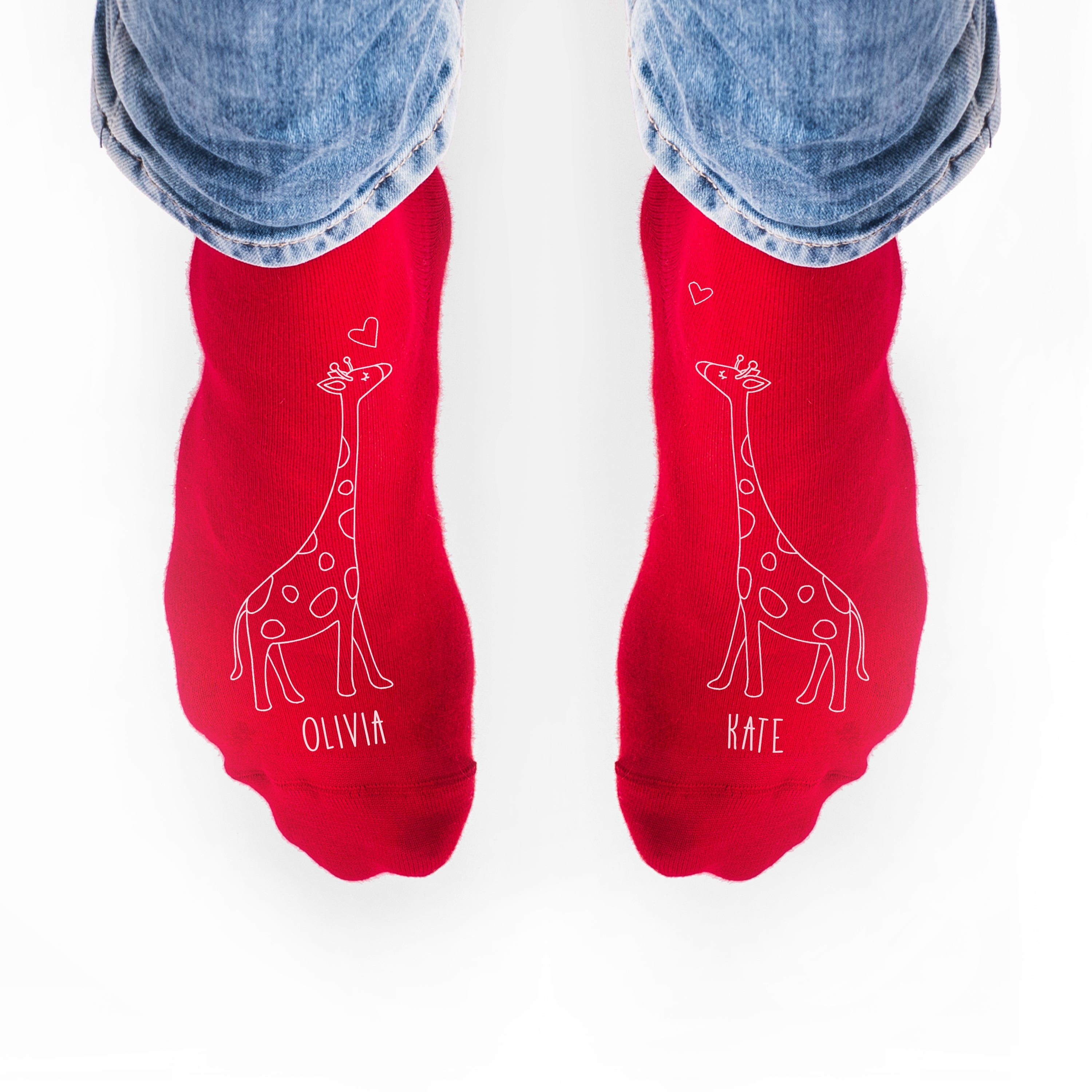 Red socks with giraffe illustrations and names 'Olivia' and 'Kate' on a white background.