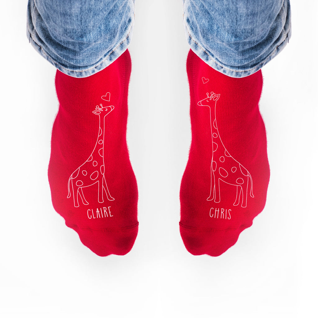 Red socks with giraffe designs and names 'Claire' and 'Chris' on a white background.