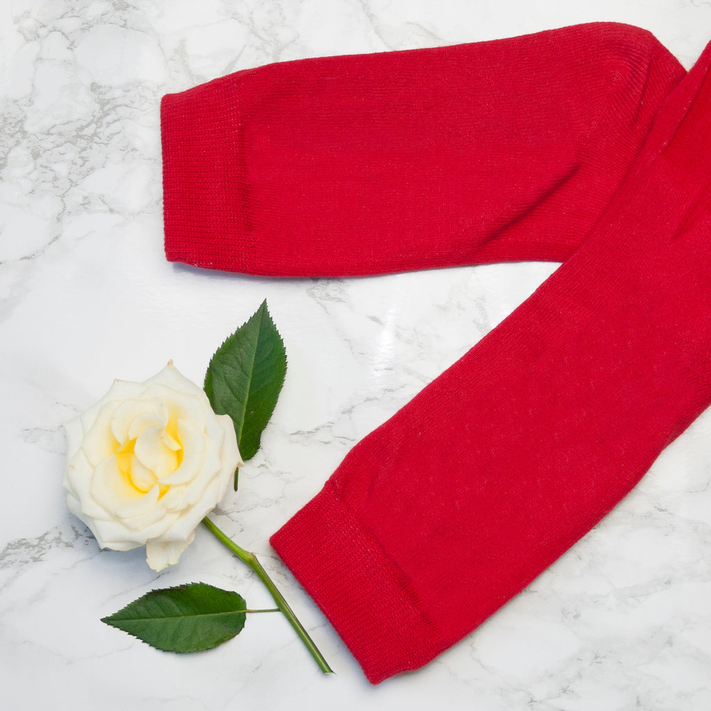 Red knitted item and white rose on a marble surface
