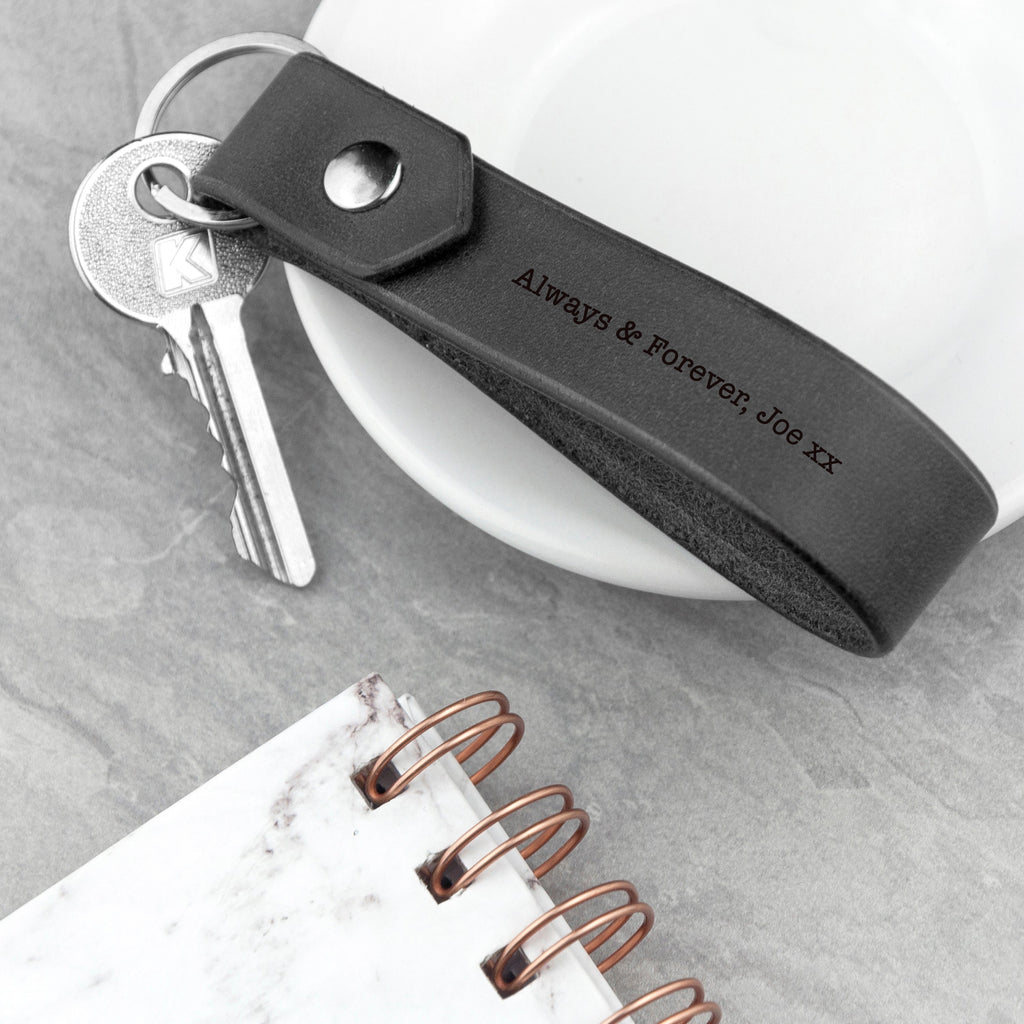 Black keychain with engraved text on a white surface