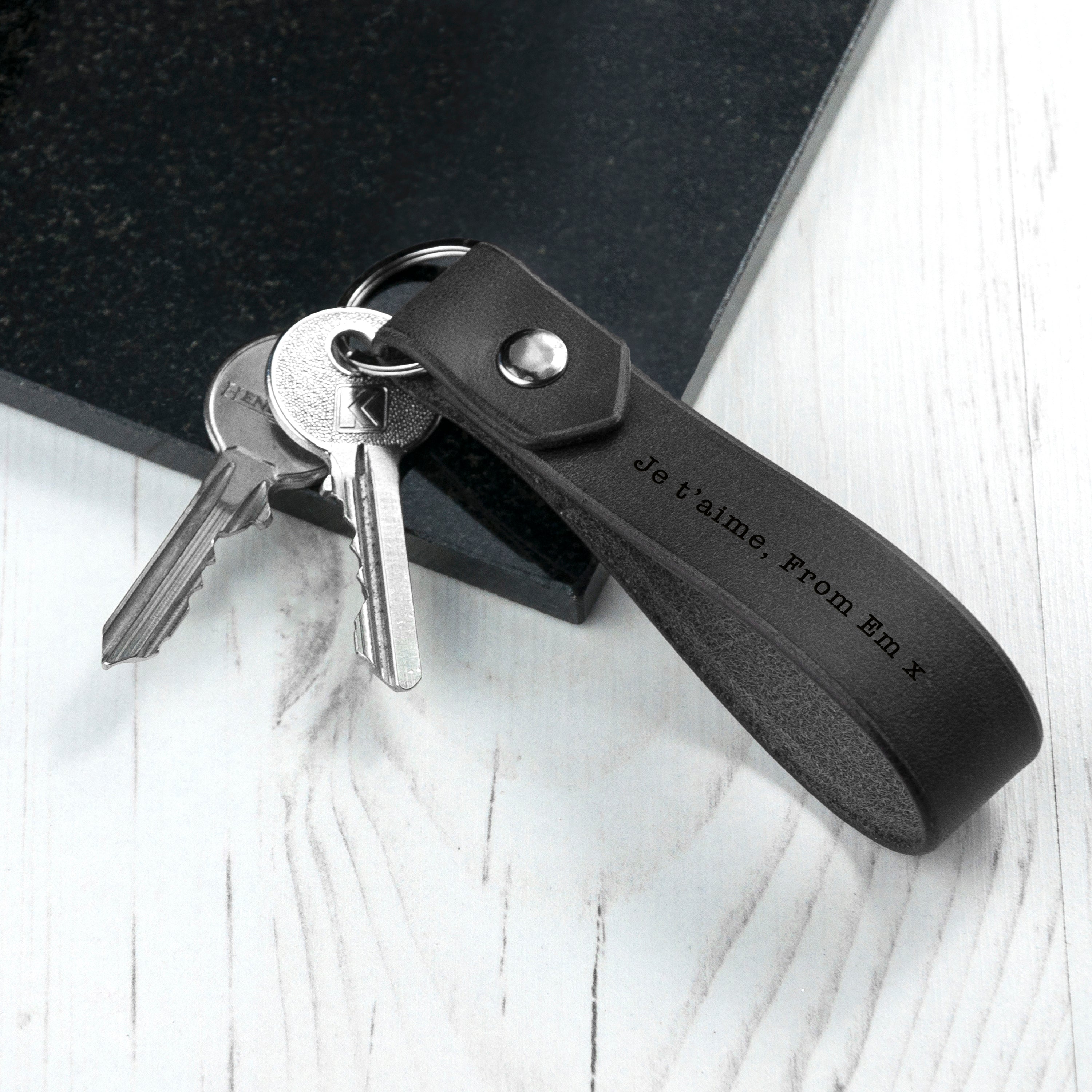 Black leather key fob with keys on a white surface