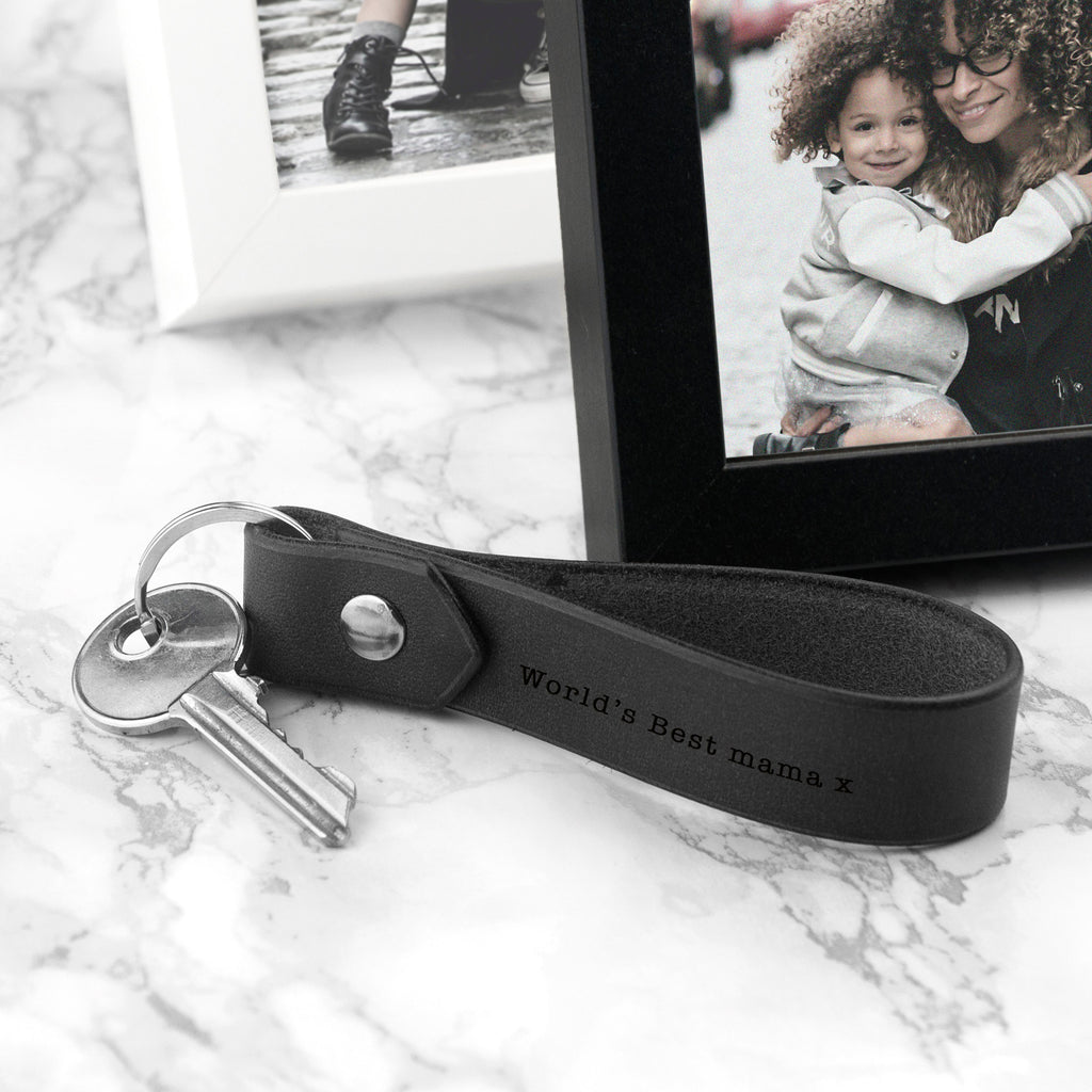 Black leather keychain with 'World's Best Mame' text on a marble surface with photos in the background.