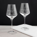 Two personalized wine glasses with 'Elizabeth & Neil EST. 2023' text on a black background.