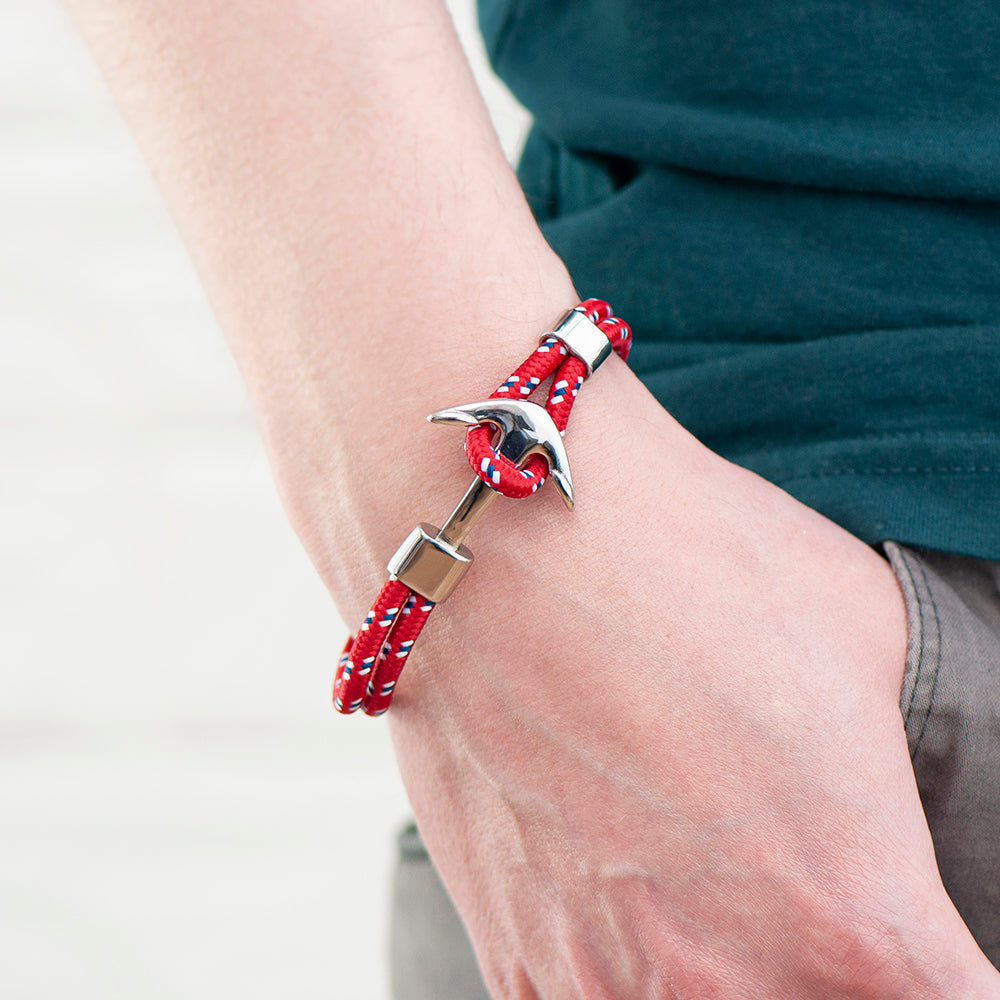 Red beaded bracelet with a silver clasp on a wrist against a neutral background