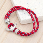 Red braided rope bracelet with silver clasp on a light wooden surface