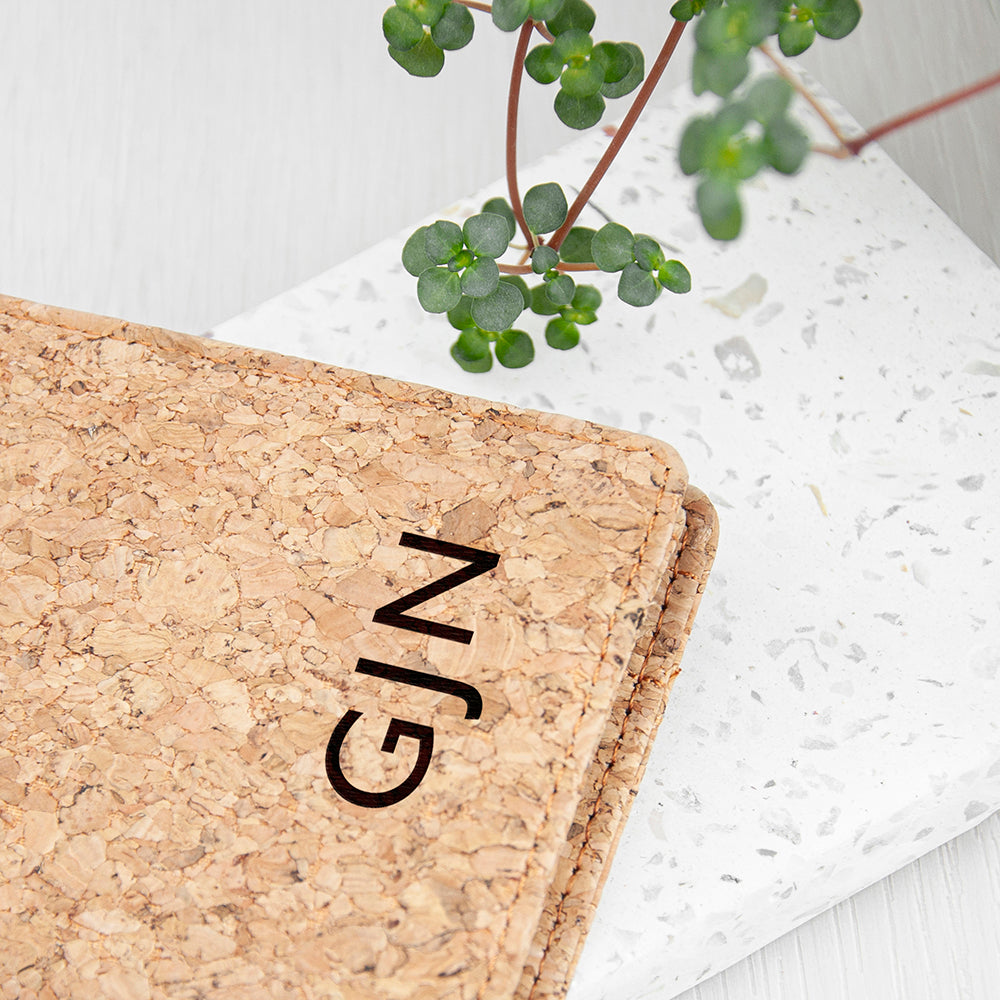 Cork board with 'GIN' engraving on a white surface with greenery