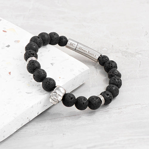 Black beaded bracelet with silver clasp on a light gray surface