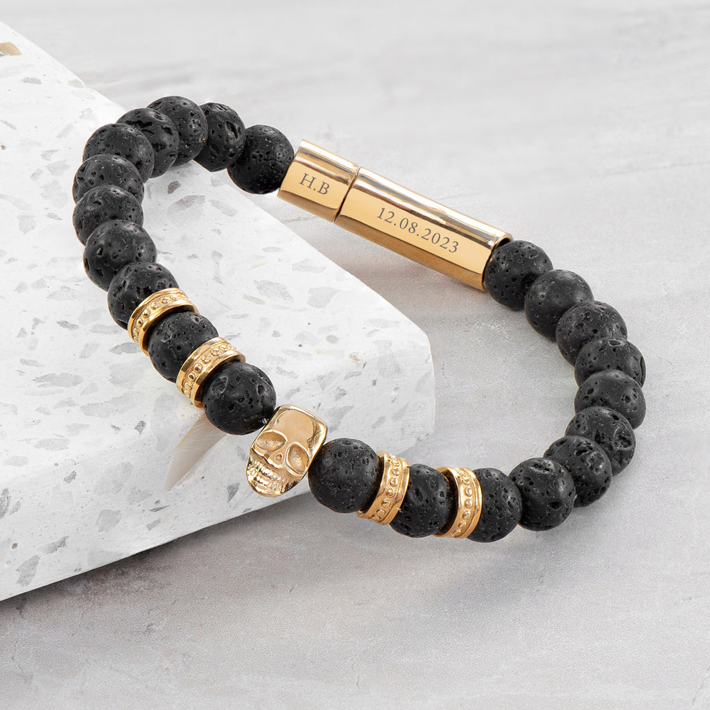 Black beaded bracelet with gold accents on a light gray surface