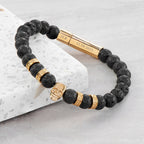 Black beaded bracelet with gold accents on a light gray surface