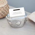 Silver decorative bowl with a card inside on a light surface