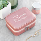 Pink jewelry box with 'Olivia's Treasure' engraving on a light gray surface.