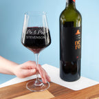 Wine glass with red wine and a bottle of wine on a wooden surface against a blue background