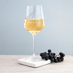Wine glass with 'Violet Wine O'Clock' text on a marble coaster with grapes, against a light gray background.