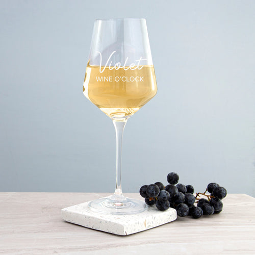 Wine glass with 'Violet Wine O'Clock' text on a marble coaster with grapes, against a light gray background.