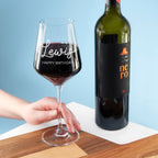Wine glass with red wine and a bottle of wine on a wooden surface with a blue background