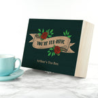 Tea box with 'You're Tea-rific' design next to a turquoise cup on a marble surface
