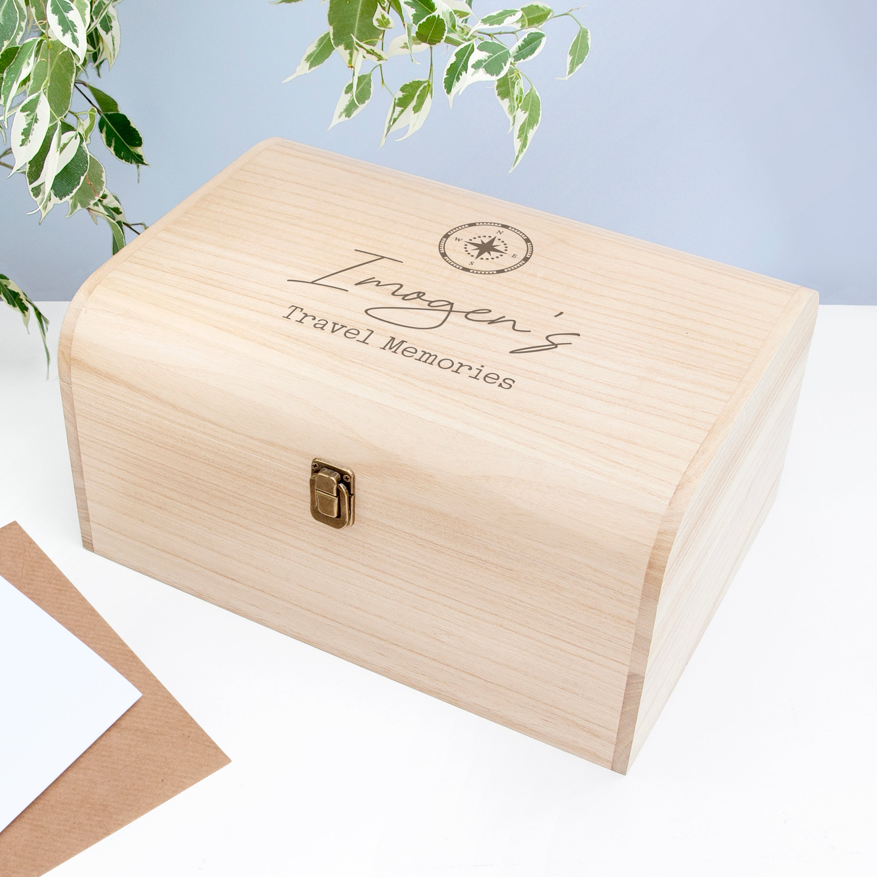Wooden box with 'Imogen's Travel Memories' engraving on a light blue background