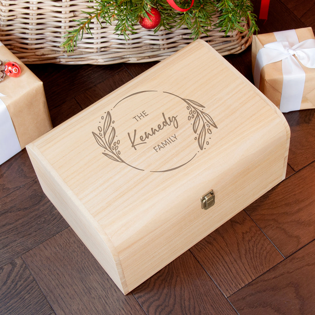 Wooden box with 'The Kennedy Family' engraving on a wooden floor with Christmas decorations.