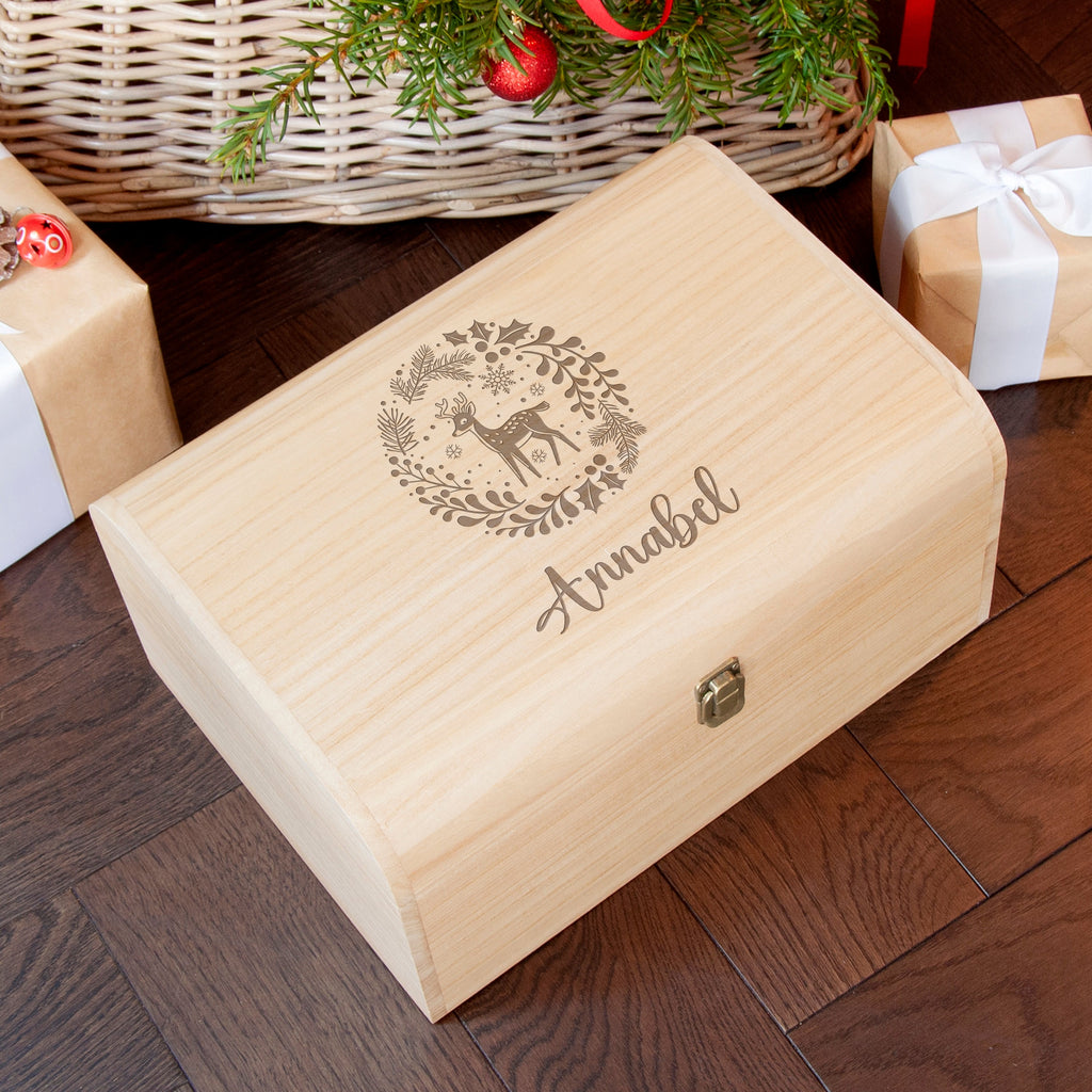 Wooden box with engraved design and name 'Annabel' on a wooden floor with Christmas decorations.