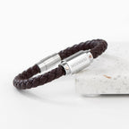Brown braided leather bracelet with silver cylindrical clasp on a white background