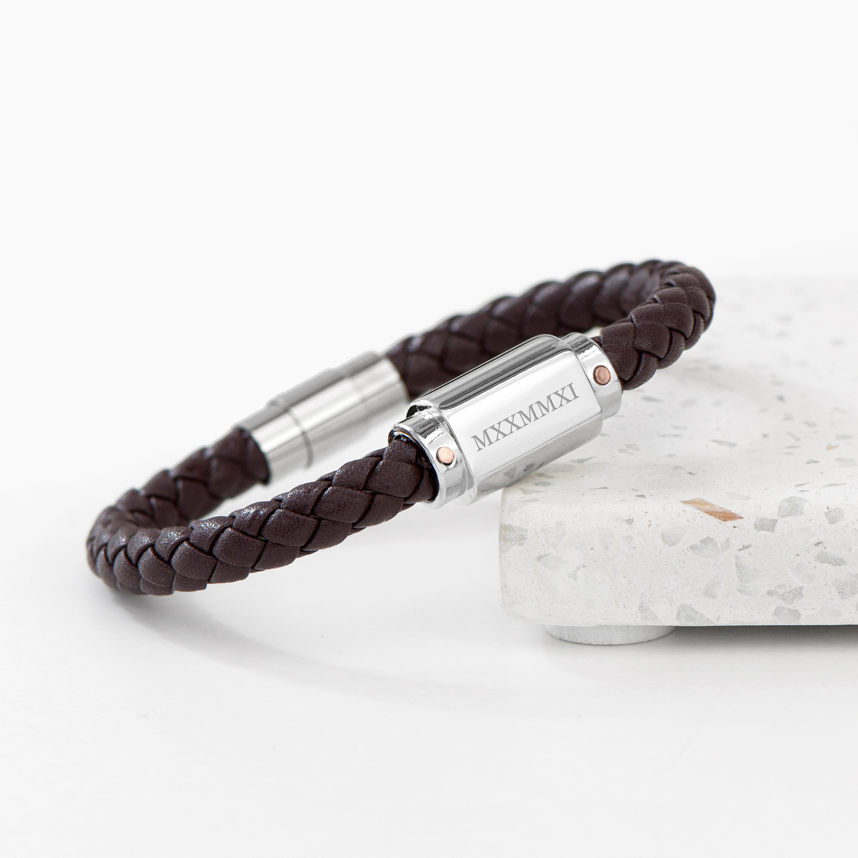 Brown braided leather bracelet with silver cylindrical clasp on a white background