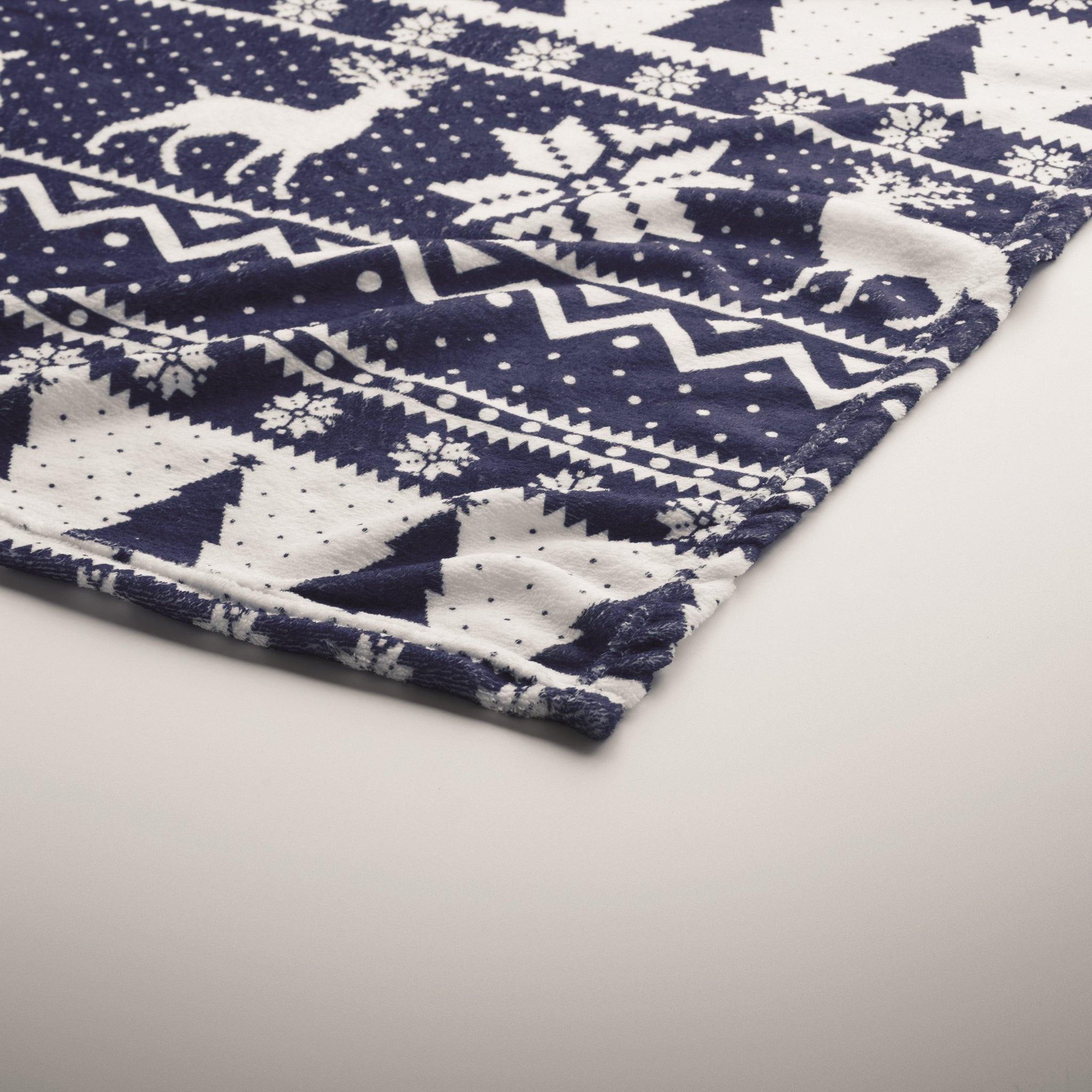 Close-up of a blue and white patterned fabric with deer and snowflake designs.