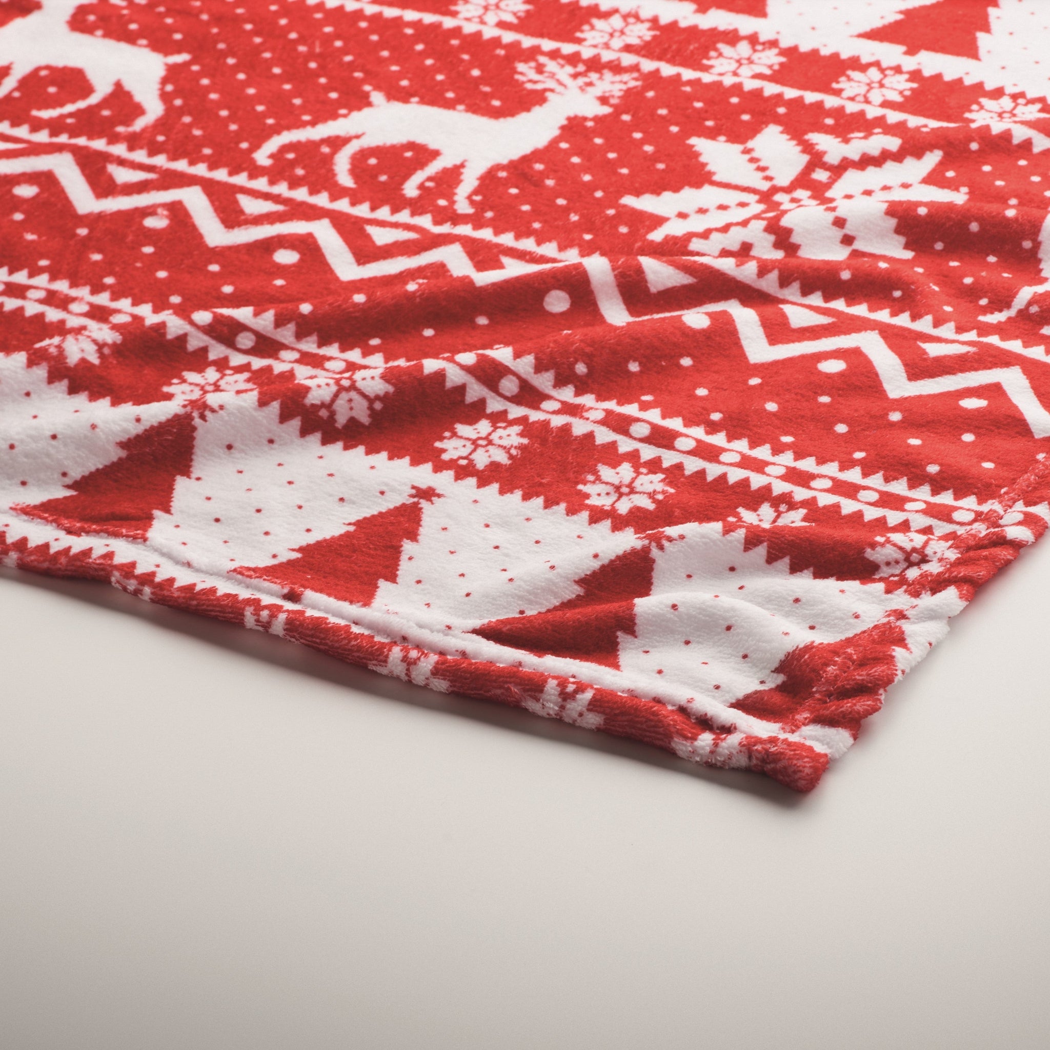 Red and white patterned fabric with reindeer and snowflakes on a light gray background