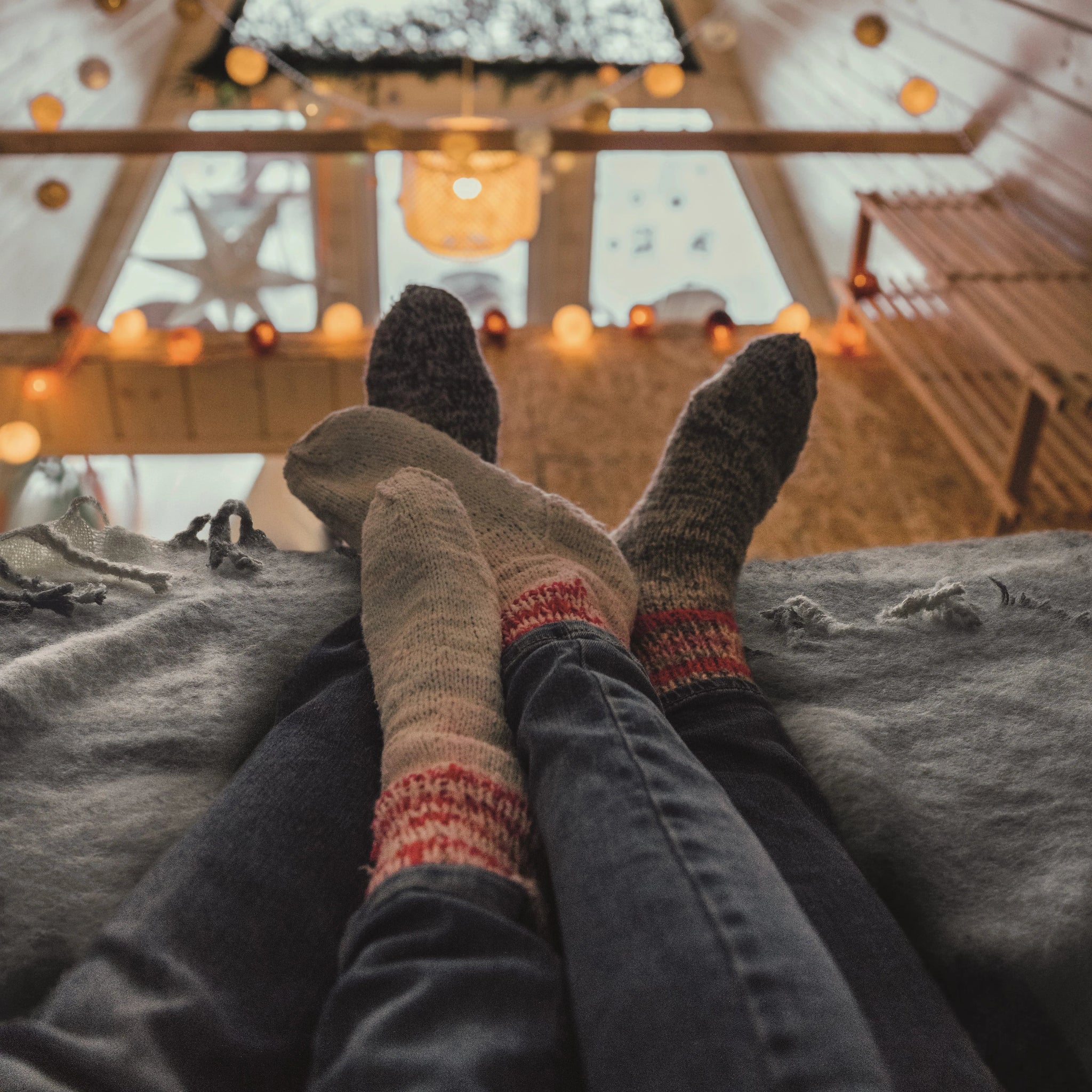 Two pairs of feet wearing patterned socks in a cozy indoor setting with warm lighting.
