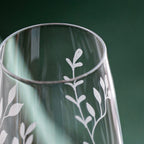 Clear glass vase with white leaf patterns on a green background